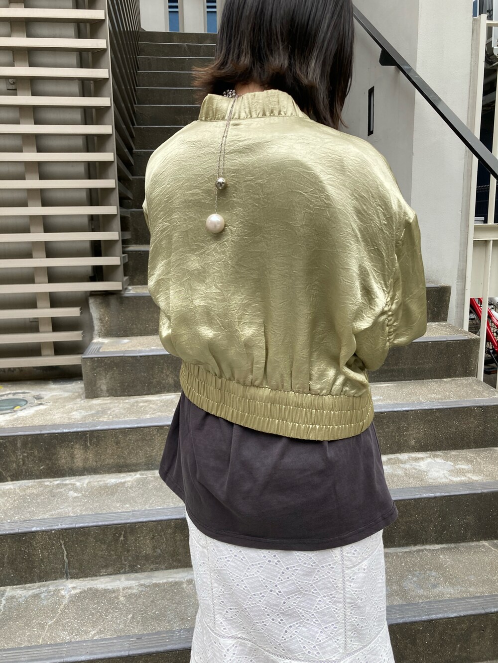 グリーン系のMA-1、グレー系のTシャツ/カットソー、ホワイト系のスカートを着用したレディースの春コーディネートの3枚目の写真