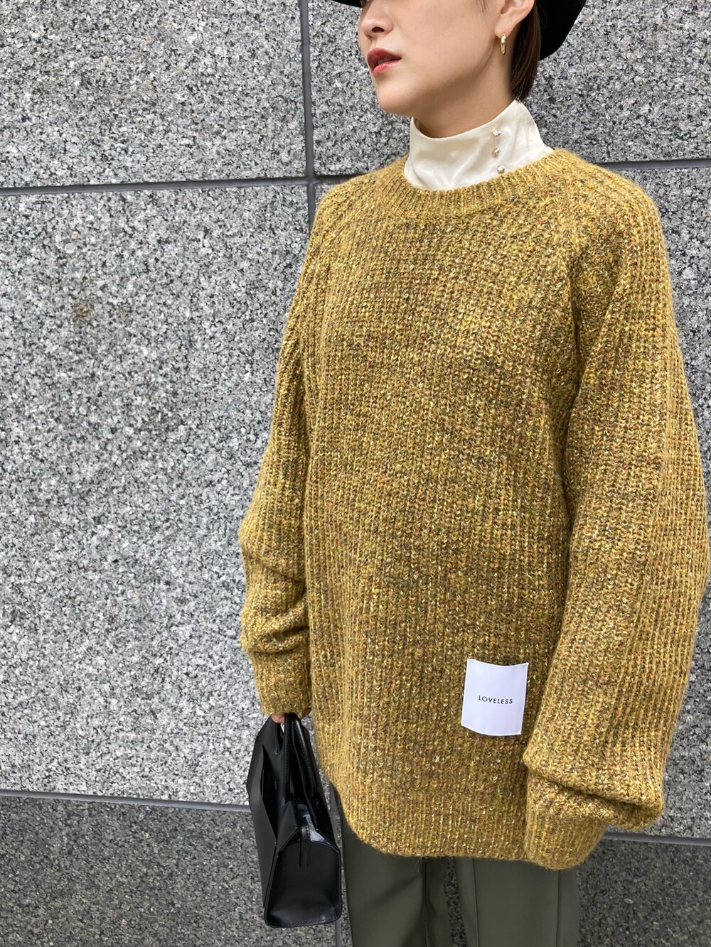 イエロー系のニット/セーター、ブラック系のショルダーバッグ、グリーン系のその他パンツを着用したレディースの秋コーディネートの2枚目の写真