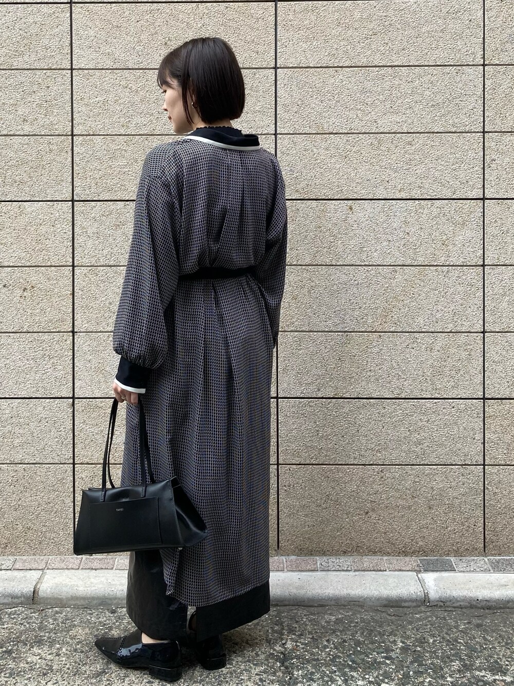 ブラック系のハンドバッグ、ブラック系のシャツワンピース、ブラック系のその他シューズを着用したレディースの秋コーディネートの2枚目の写真