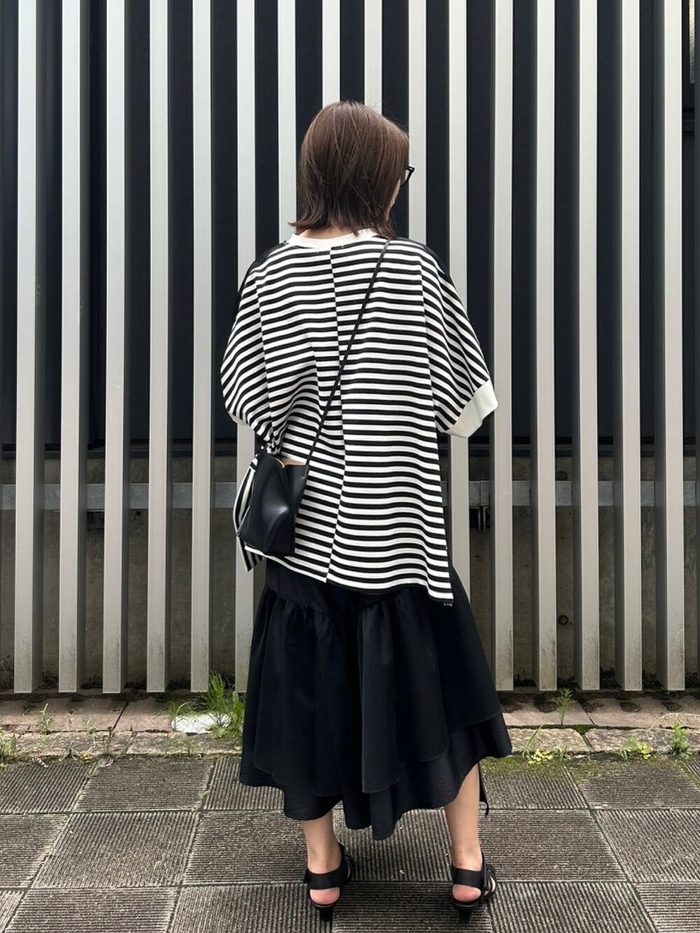 ブラック系のスカート、ブラック系のサンダル、ブラック系のTシャツ/カットソーを着用したレディースの夏コーディネートの2枚目の写真