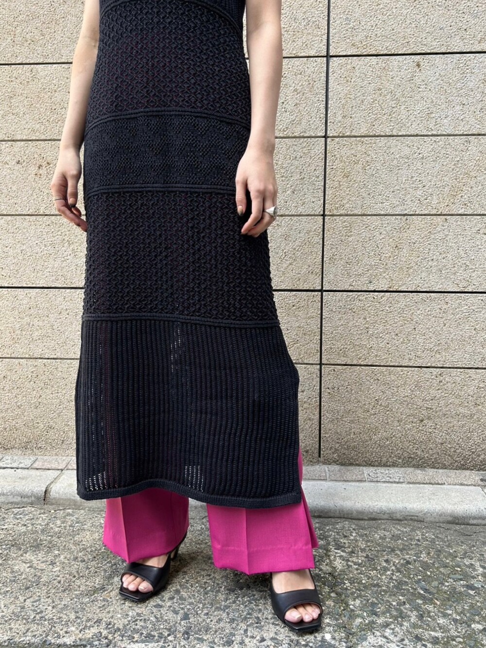 ピンク系のパンツ、ブラック系のニット/セーター、ブラック系のワンピースを着用したレディースの春コーディネートの5枚目の写真