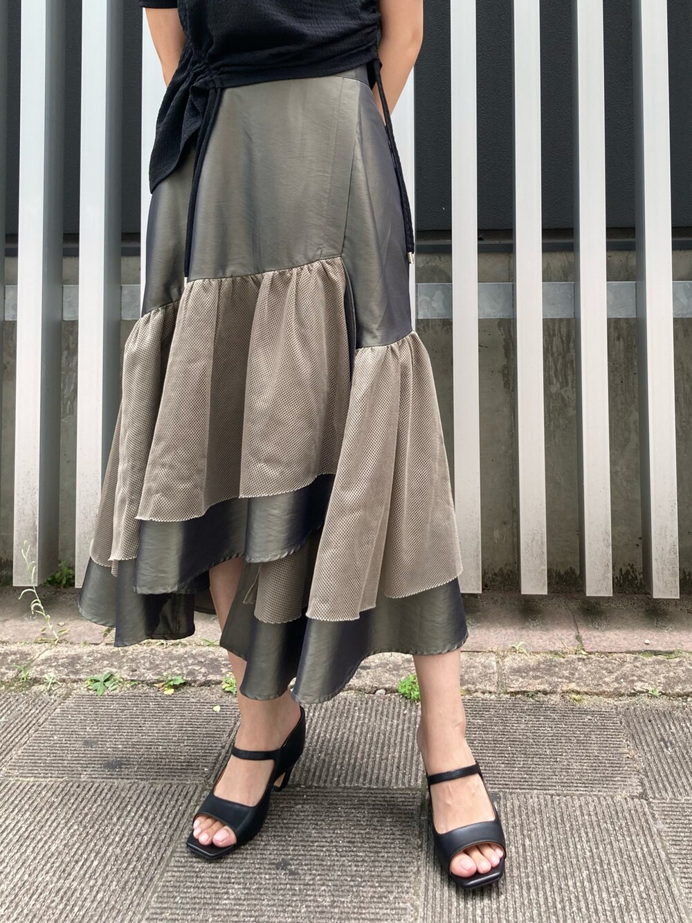 ブラック系のサンダル、グリーン系のスカート、ブラック系のTシャツ/カットソーを着用したレディースの夏コーディネートの3枚目の写真