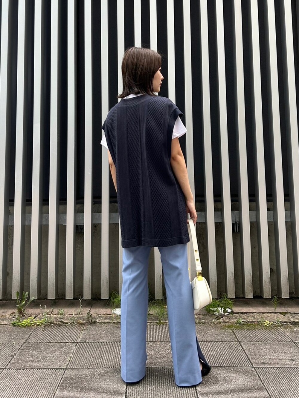 ホワイト系のハンドバッグ、ブルー系のベスト、ブルー系のその他パンツを着用したレディースの夏コーディネートの2枚目の写真