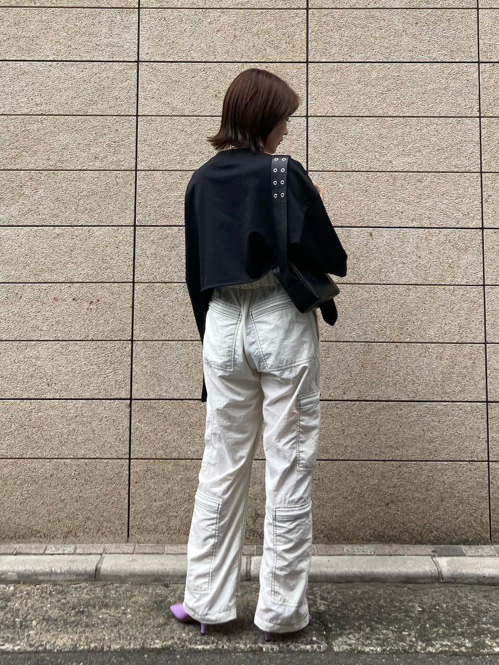 ブラック系のTシャツ/カットソー、ブラック系のショルダーバッグ、ホワイト系のパンツを着用したレディースの春コーディネートの2枚目の写真