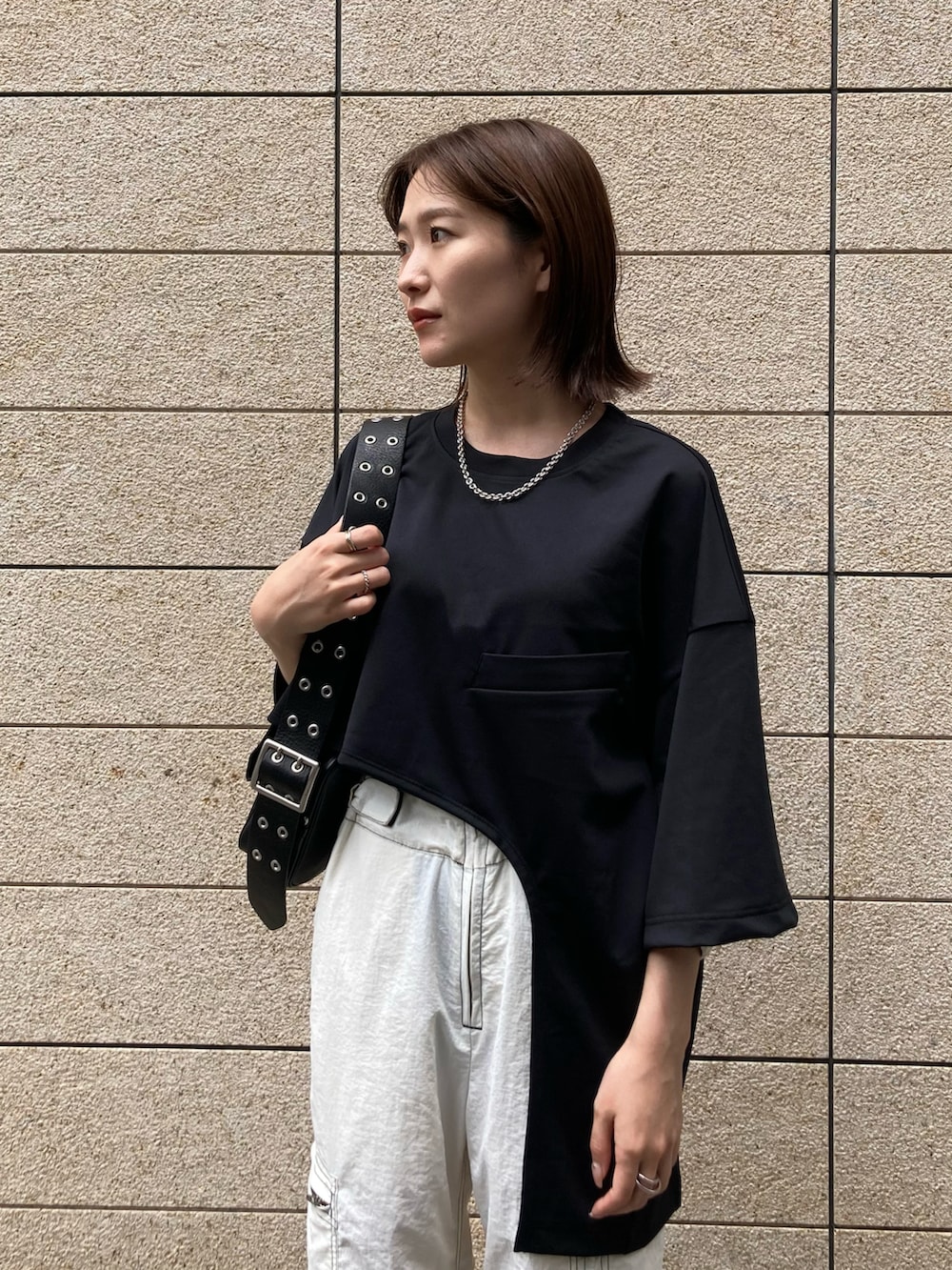 ブラック系のTシャツ/カットソー、ブラック系のショルダーバッグ、ホワイト系のパンツを着用したレディースの春コーディネートの3枚目の写真