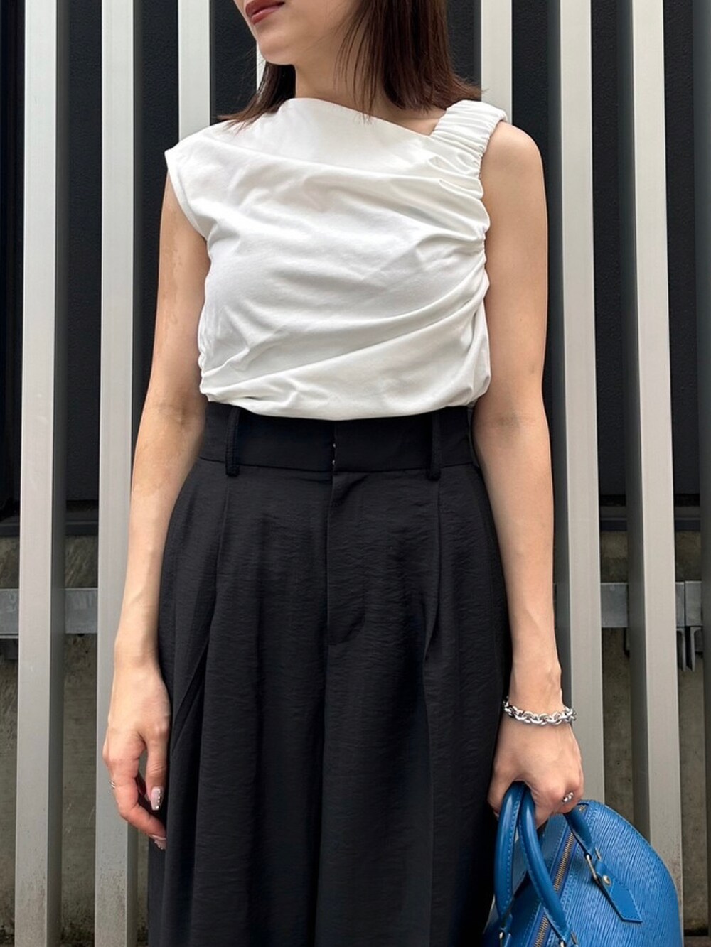 ブラック系のスラックス、ホワイト系のTシャツ/カットソー、ブラック系のサンダルを着用したレディースの夏コーディネートの2枚目の写真