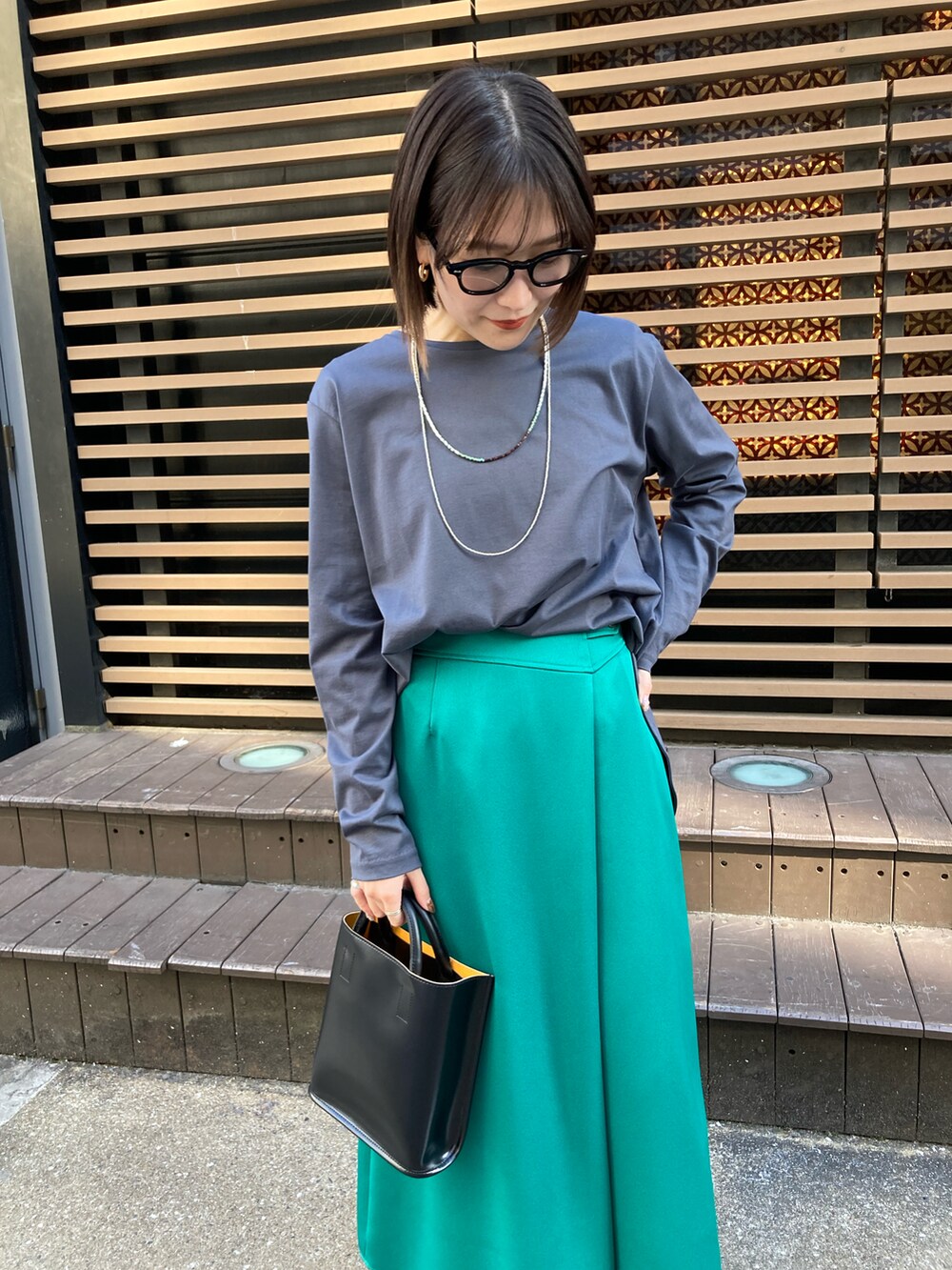 グリーン系のスカート、ブラック系のハンドバッグ、グレー系のその他トップスを着用したレディースの春コーディネートの2枚目の写真