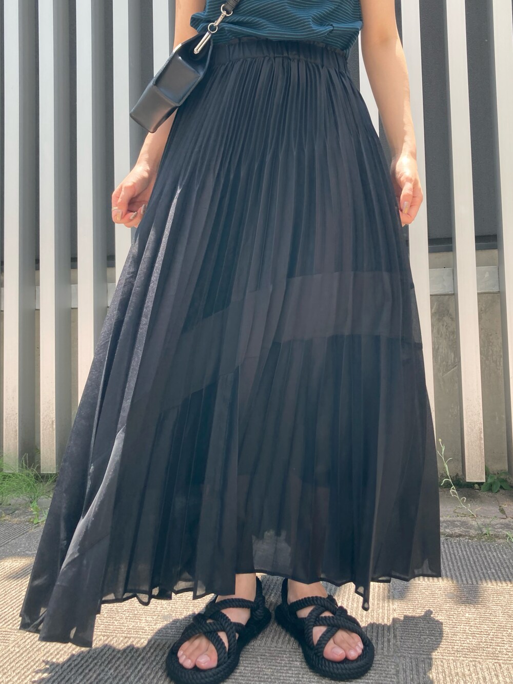 ブラック系のスカート、ブラック系のサンダル、ブラック系のショルダーバッグを着用したレディースの夏コーディネートの3枚目の写真