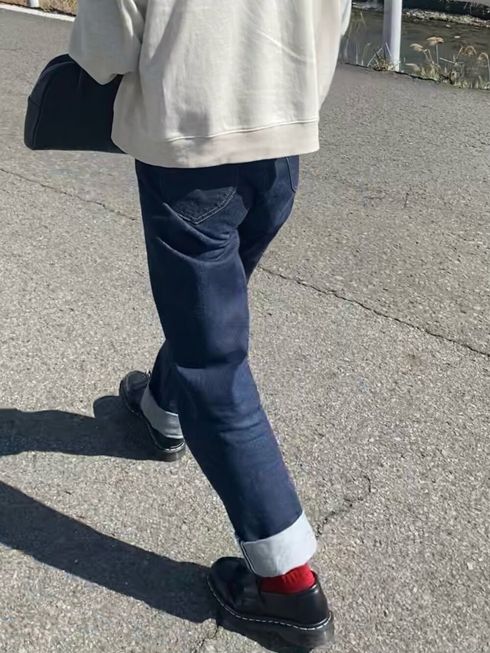 ブラック系のバッグ、ブルー系のデニムパンツ、ブラック系のローファーを着用したレディースの春コーディネートの2枚目の写真