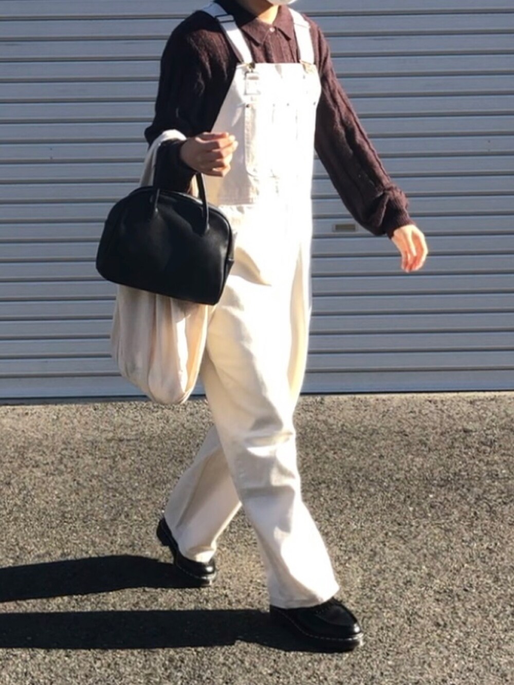 ホワイト系のサロペット/オーバーオール、ブラウン系のニット/セーター、ブラック系のローファーを着用したレディースの冬コーディネートの2枚目の写真