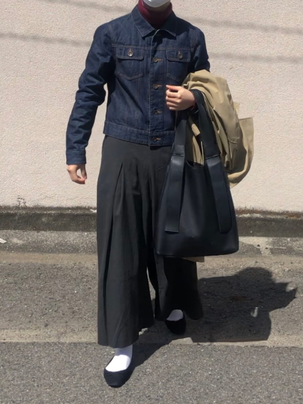 ブラック系のトートバッグ、ブラック系のパンツ、ブルー系のデニムジャケットを着用したレディースの春コーディネートの3枚目の写真