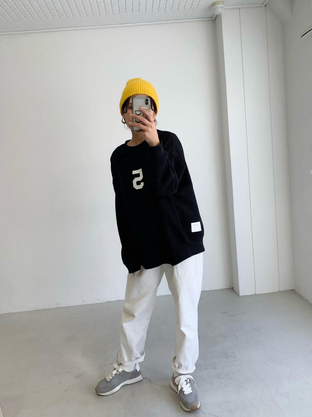 ブラック系のスウェット、ブラック系のその他アウター、イエロー系のニットキャップ/ビーニーを着用したレディースの冬コーディネートの2枚目の写真