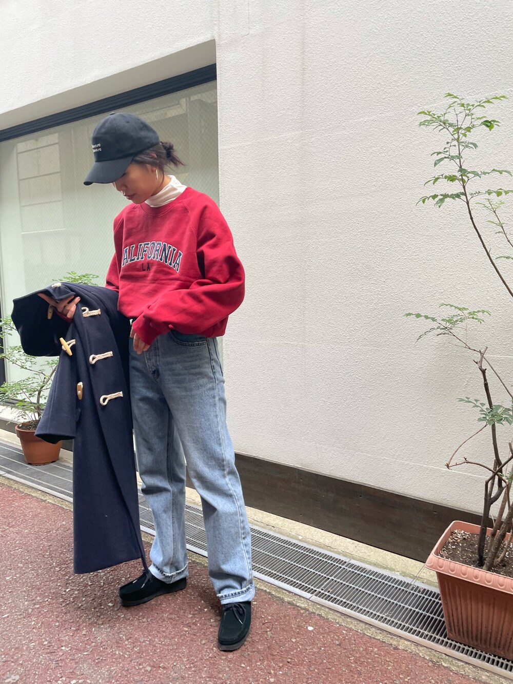 レッド系のスウェット、ブルー系のダッフルコート、ブルー系のデニムパンツを着用したレディースの冬コーディネートの2枚目の写真