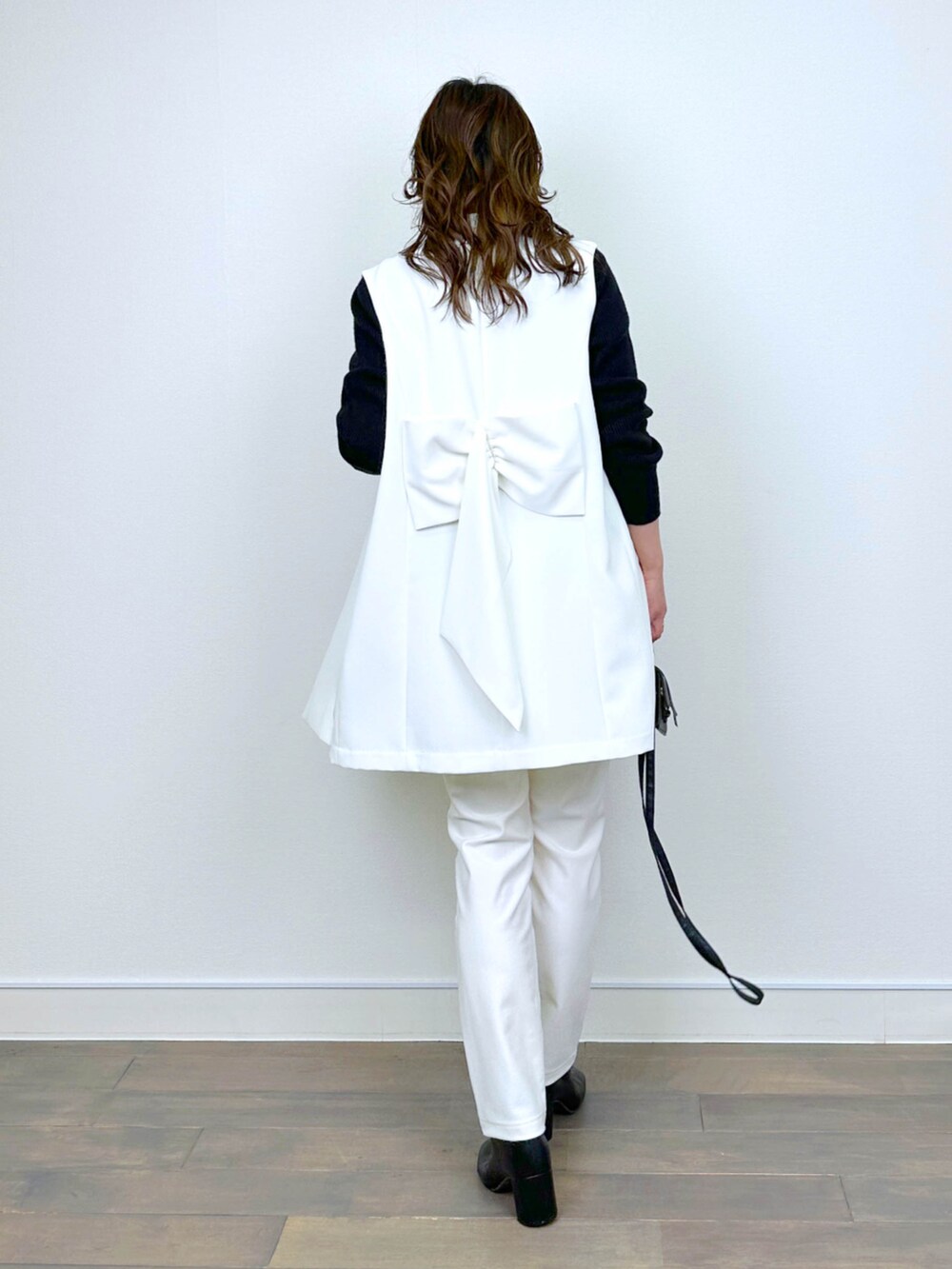 ホワイト系のベスト、ブラック系のニット/セーター、ホワイト系のその他パンツを着用したレディースの冬コーディネートの3枚目の写真