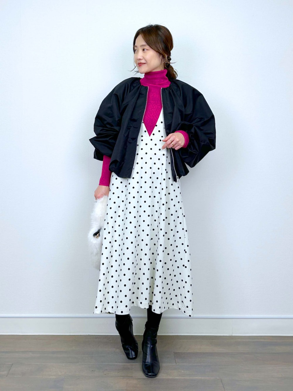 ブラック系のブルゾン、レッド系のニット/セーター、ホワイト系のジャンパースカートを着用したレディースの冬コーディネートの5枚目の写真