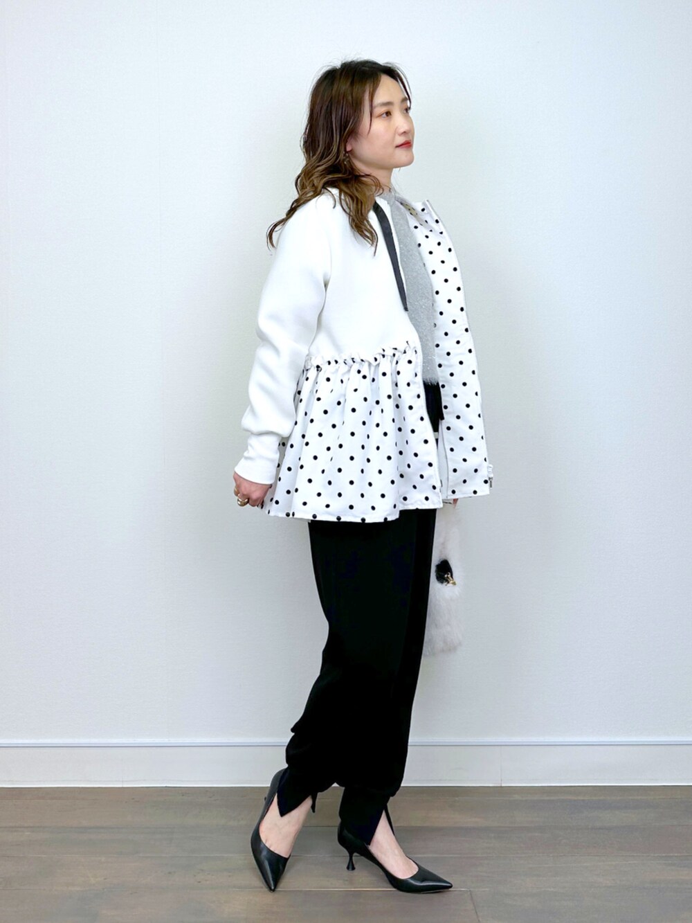 シルバー系のニット/セーター、ブラック系のその他パンツ、ホワイト系のパーカーを着用したレディースの冬コーディネートの2枚目の写真