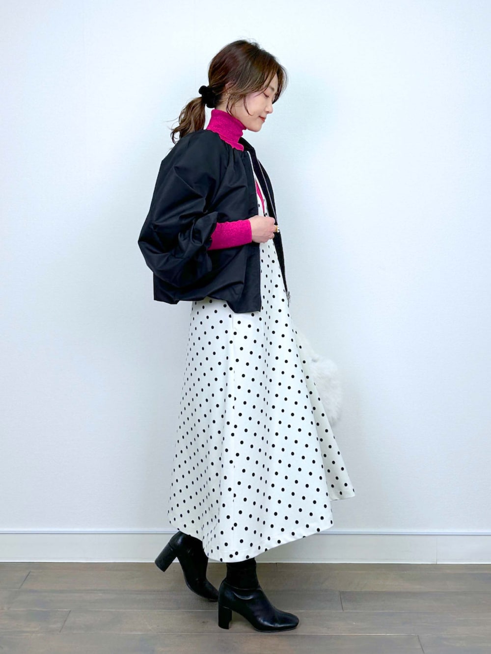 ブラック系のブルゾン、レッド系のニット/セーター、ホワイト系のジャンパースカートを着用したレディースの冬コーディネートの2枚目の写真