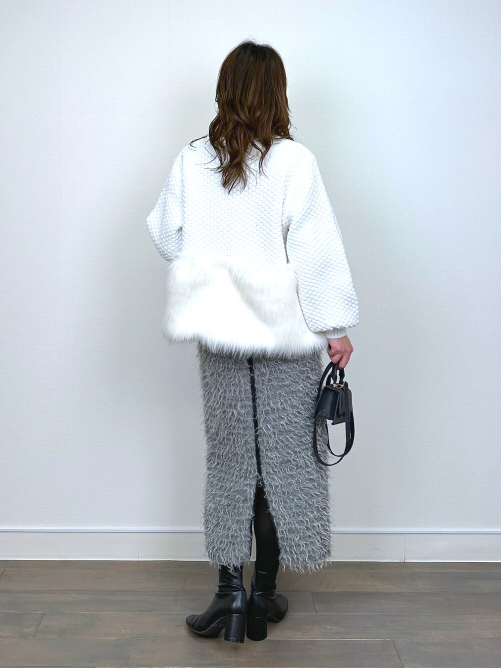 ホワイト系のカーディガン/ボレロ、イエロー系のニット/セーター、グレー系のスカートを着用したレディースの秋コーディネートの3枚目の写真