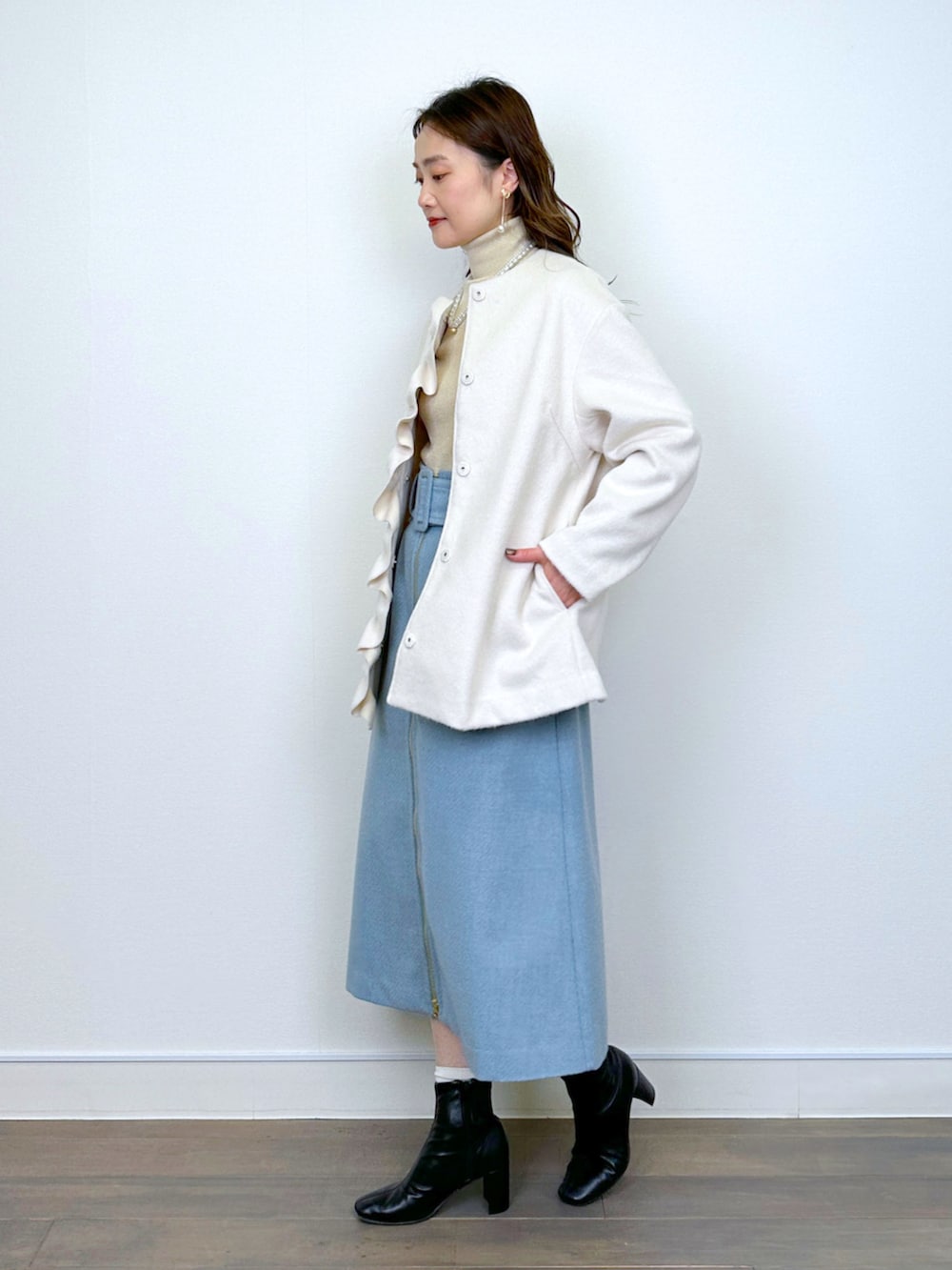 ベージュ系のニット/セーター、ホワイト系のノーカラーコート、ブルー系のスカートを着用したレディースの冬コーディネートの4枚目の写真