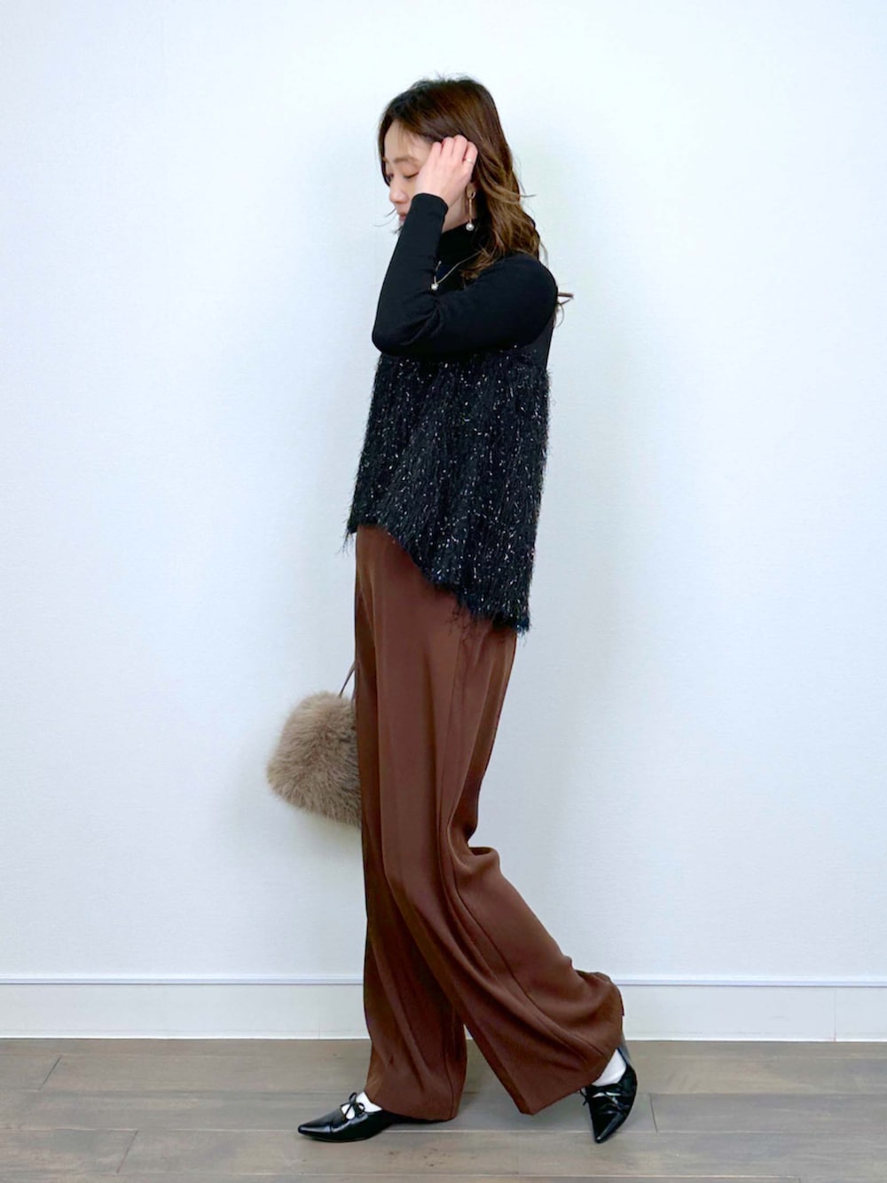 ブラウン系のスラックス、ブラック系のシャツ/ブラウス、ブラック系のニット/セーターを着用したレディースの冬コーディネートの2枚目の写真