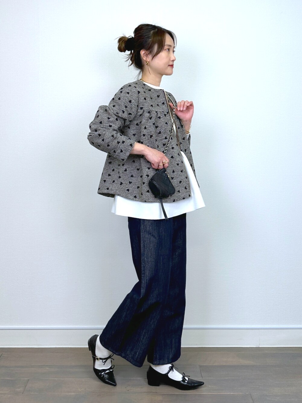 ブラウン系のブルゾン、ホワイト系のニット/セーター、ブルー系のデニムパンツを着用したレディースの冬コーディネートの4枚目の写真