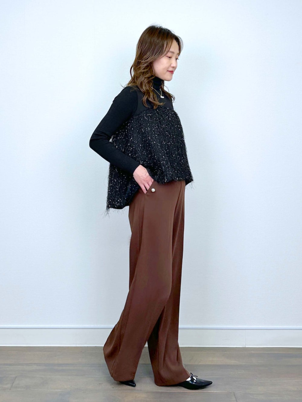 ブラウン系のスラックス、ブラック系のシャツ/ブラウス、ブラック系のニット/セーターを着用したレディースの冬コーディネートの4枚目の写真