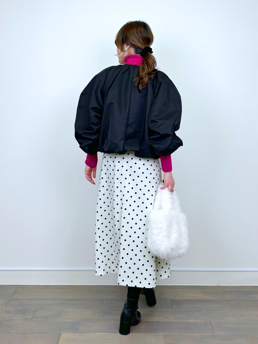 ブラック系のブルゾン、レッド系のニット/セーター、ホワイト系のジャンパースカートを着用したレディースの冬コーディネートの3枚目の写真