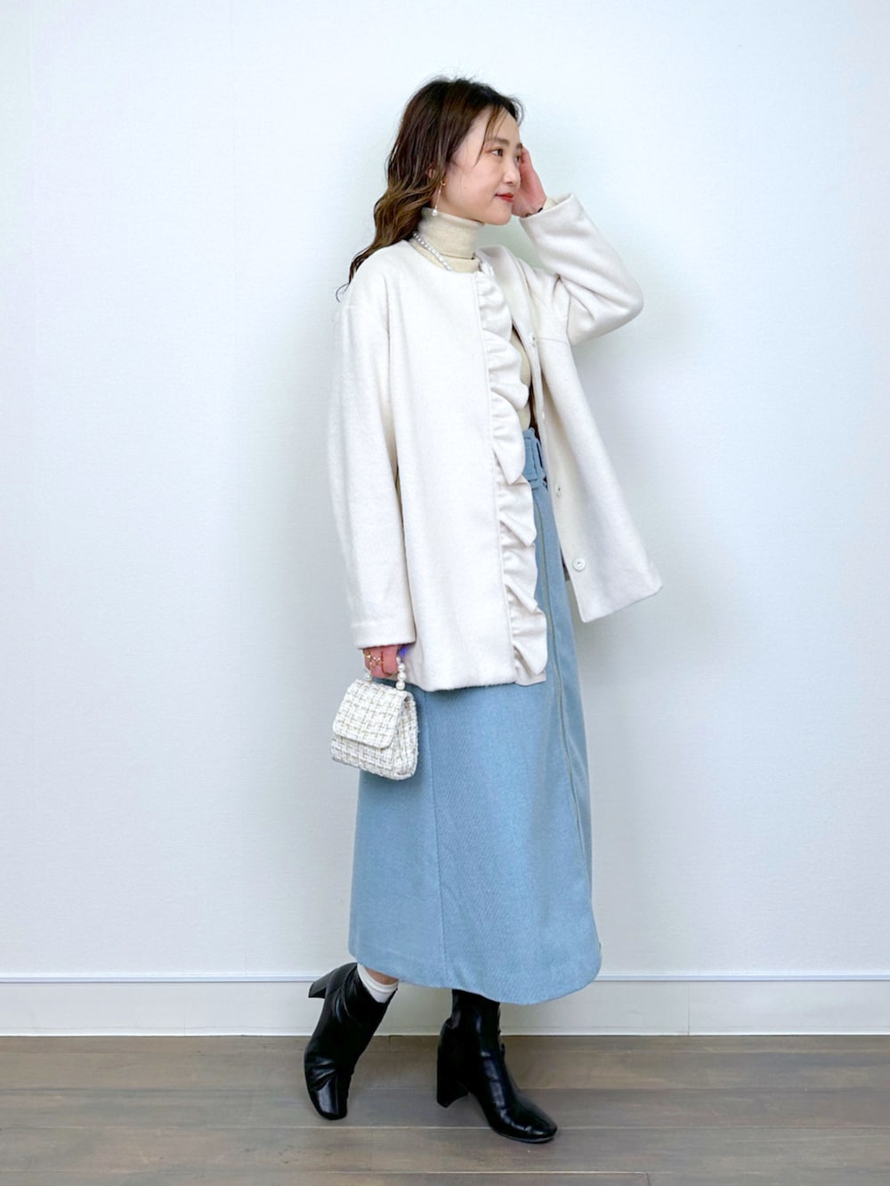 ベージュ系のニット/セーター、ホワイト系のノーカラーコート、ブルー系のスカートを着用したレディースの冬コーディネートの2枚目の写真