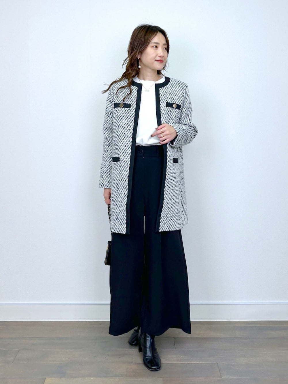 ブラック系のノーカラーコート、ホワイト系のニット/セーター、ブラック系のその他パンツを着用したレディースの冬コーディネートの5枚目の写真