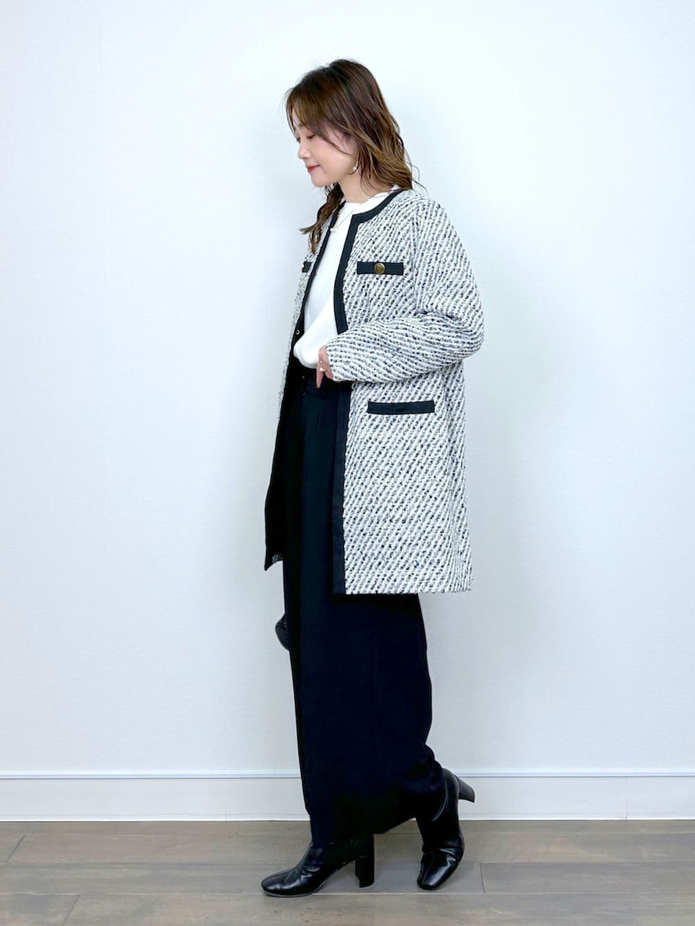 ブラック系のノーカラーコート、ホワイト系のニット/セーター、ブラック系のその他パンツを着用したレディースの冬コーディネートの4枚目の写真