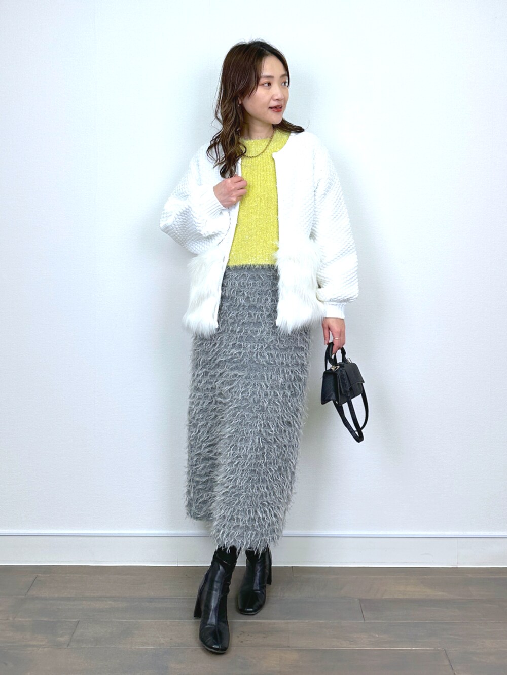 ホワイト系のカーディガン/ボレロ、イエロー系のニット/セーター、グレー系のスカートを着用したレディースの秋コーディネートの5枚目の写真