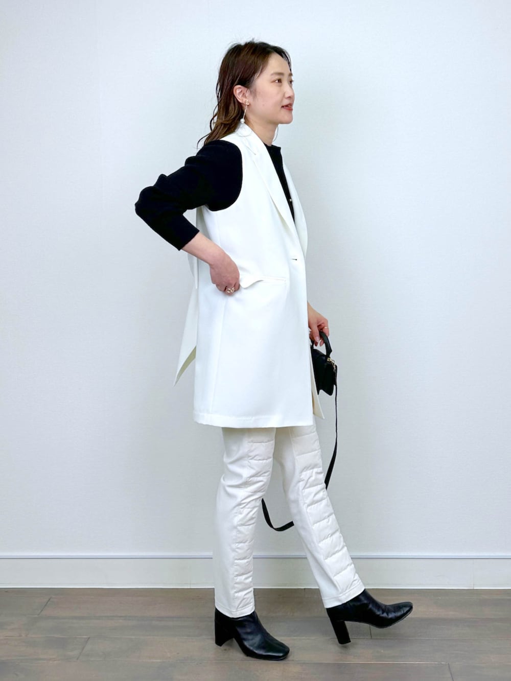 ホワイト系のベスト、ブラック系のニット/セーター、ホワイト系のその他パンツを着用したレディースの冬コーディネートの2枚目の写真