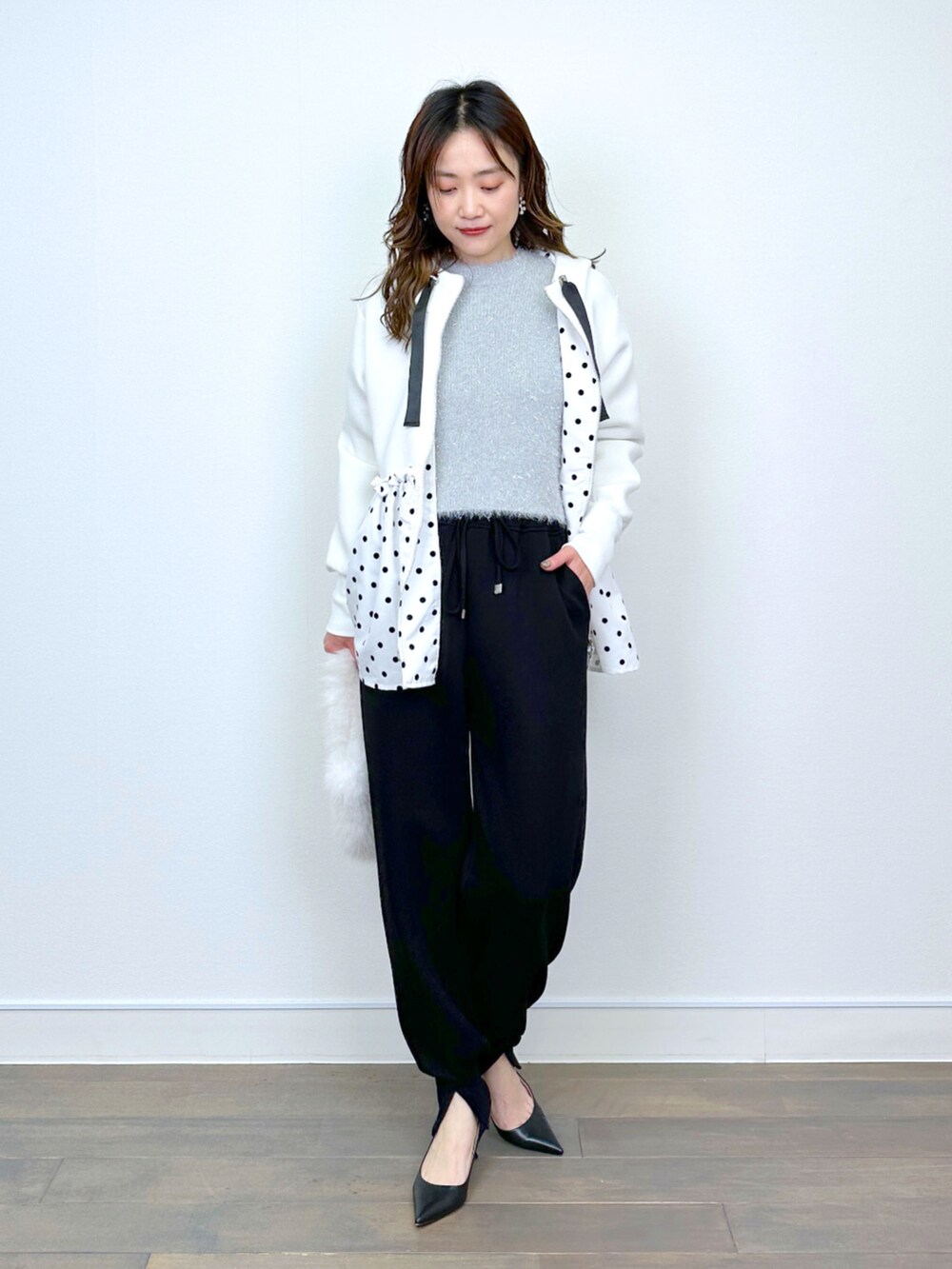 シルバー系のニット/セーター、ブラック系のその他パンツ、ホワイト系のパーカーを着用したレディースの冬コーディネートの5枚目の写真