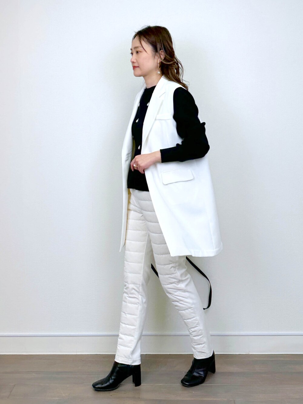 ホワイト系のベスト、ブラック系のニット/セーター、ホワイト系のその他パンツを着用したレディースの冬コーディネートの4枚目の写真