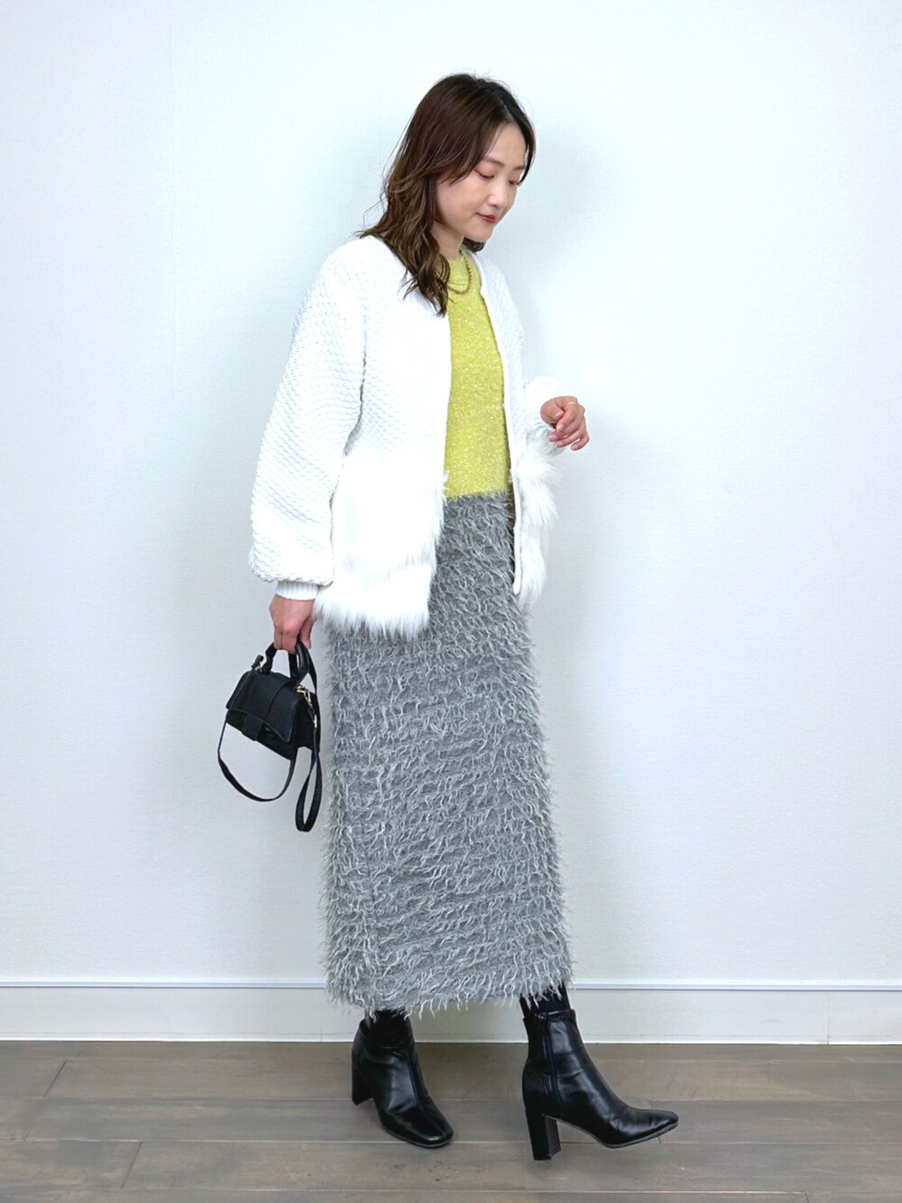 ホワイト系のカーディガン/ボレロ、イエロー系のニット/セーター、グレー系のスカートを着用したレディースの秋コーディネートの4枚目の写真