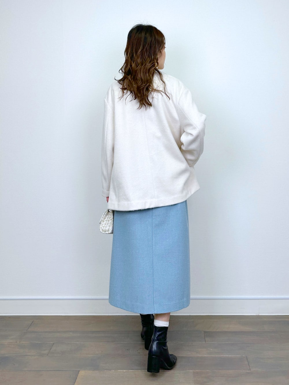 ベージュ系のニット/セーター、ホワイト系のノーカラーコート、ブルー系のスカートを着用したレディースの冬コーディネートの3枚目の写真