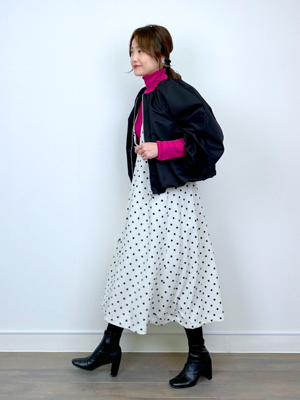 ブラック系のブルゾン、レッド系のニット/セーター、ホワイト系のジャンパースカートを着用したレディースの冬コーディネートの4枚目の写真