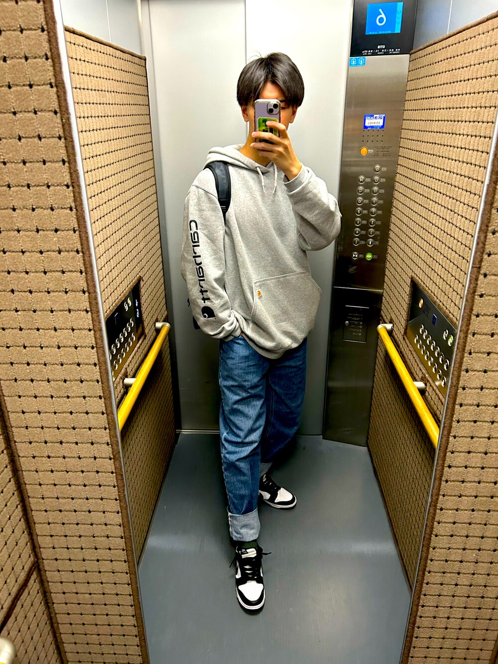 グレー系のパーカー、ブラック系のスニーカー、ブルー系のデニムパンツを着用したメンズの秋コーディネートの3枚目の写真