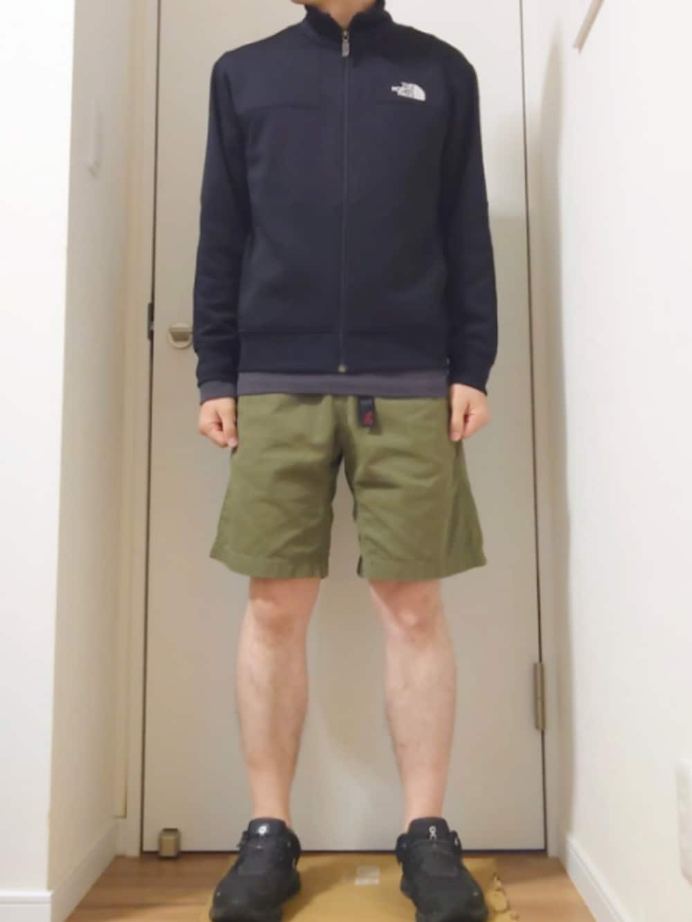 ブラック系のその他アウター、グレー系のTシャツ/カットソー、グリーン系のチノパンツを着用したメンズの秋コーディネートの2枚目の写真