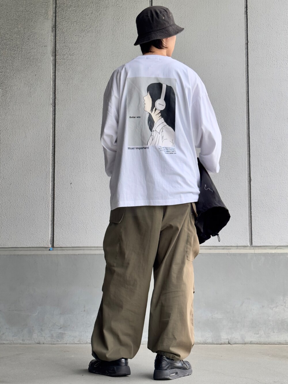 グリーン系のカーゴパンツ、ブラック系のスニーカー、ブラック系のベストを着用したメンズの春コーディネートの2枚目の写真