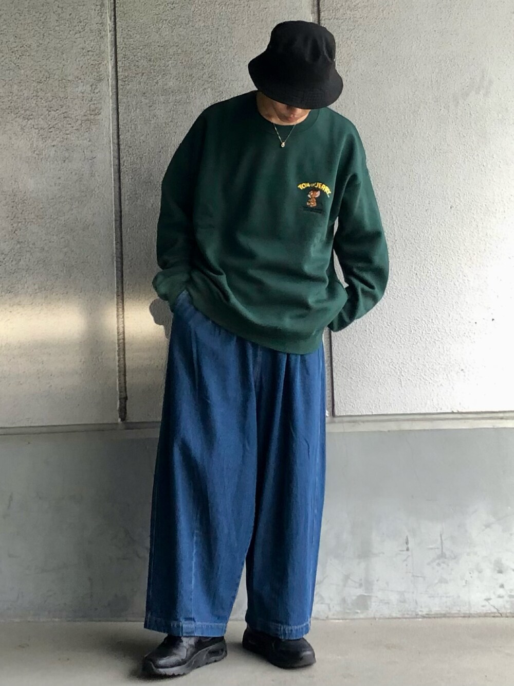 グリーン系のスウェット、ブルー系のデニムパンツ、ブラック系のスニーカーを着用したメンズの冬コーディネートの2枚目の写真