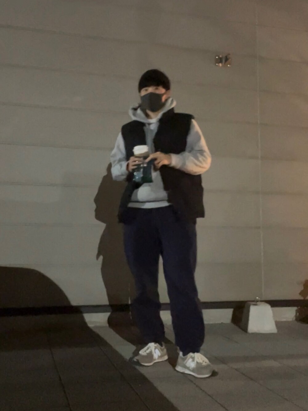 ブルー系のスウェットパンツ、グレー系のパーカー、ブラック系のダウンベストを着用したメンズの冬コーディネートの2枚目の写真