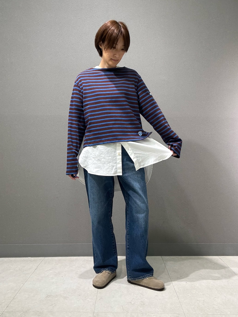 ブラウン系のTシャツ/カットソー、ホワイト系のシャツ/ブラウス、ブルー系のデニムパンツを着用したレディースの秋コーディネートの2枚目の写真