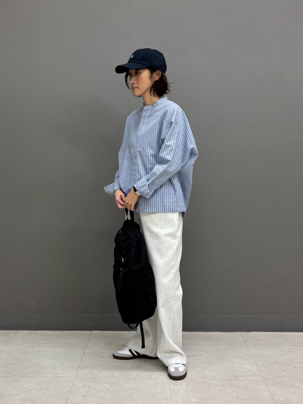 ブルー系のシャツ/ブラウス、ブラック系のバックパック/リュック、ホワイト系のスニーカーを着用したレディースの冬コーディネートの2枚目の写真