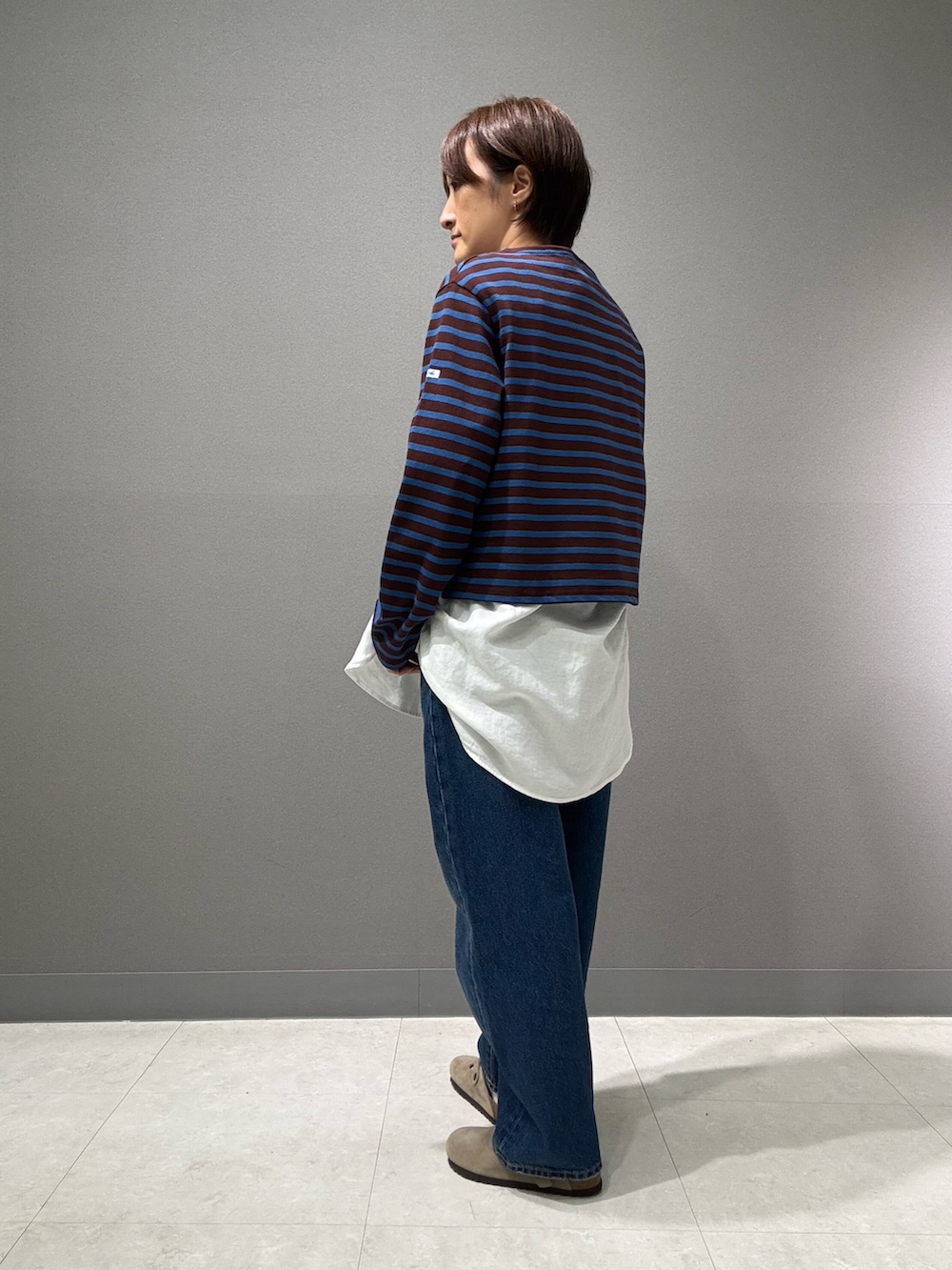 ブラウン系のTシャツ/カットソー、ホワイト系のシャツ/ブラウス、ブルー系のデニムパンツを着用したレディースの秋コーディネートの3枚目の写真