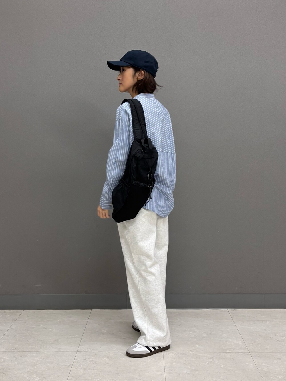 ブルー系のシャツ/ブラウス、ブラック系のバックパック/リュック、ホワイト系のスニーカーを着用したレディースの冬コーディネートの3枚目の写真