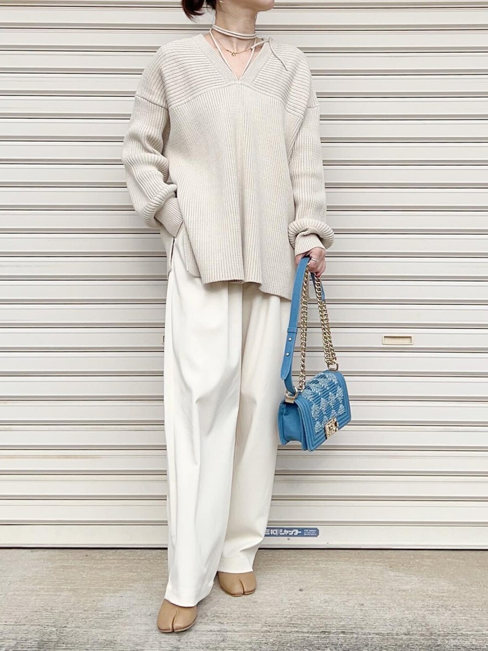 ホワイト系のニット/セーター、ホワイト系のスラックス、ベージュ系のブーツを着用したレディースの冬コーディネートの3枚目の写真