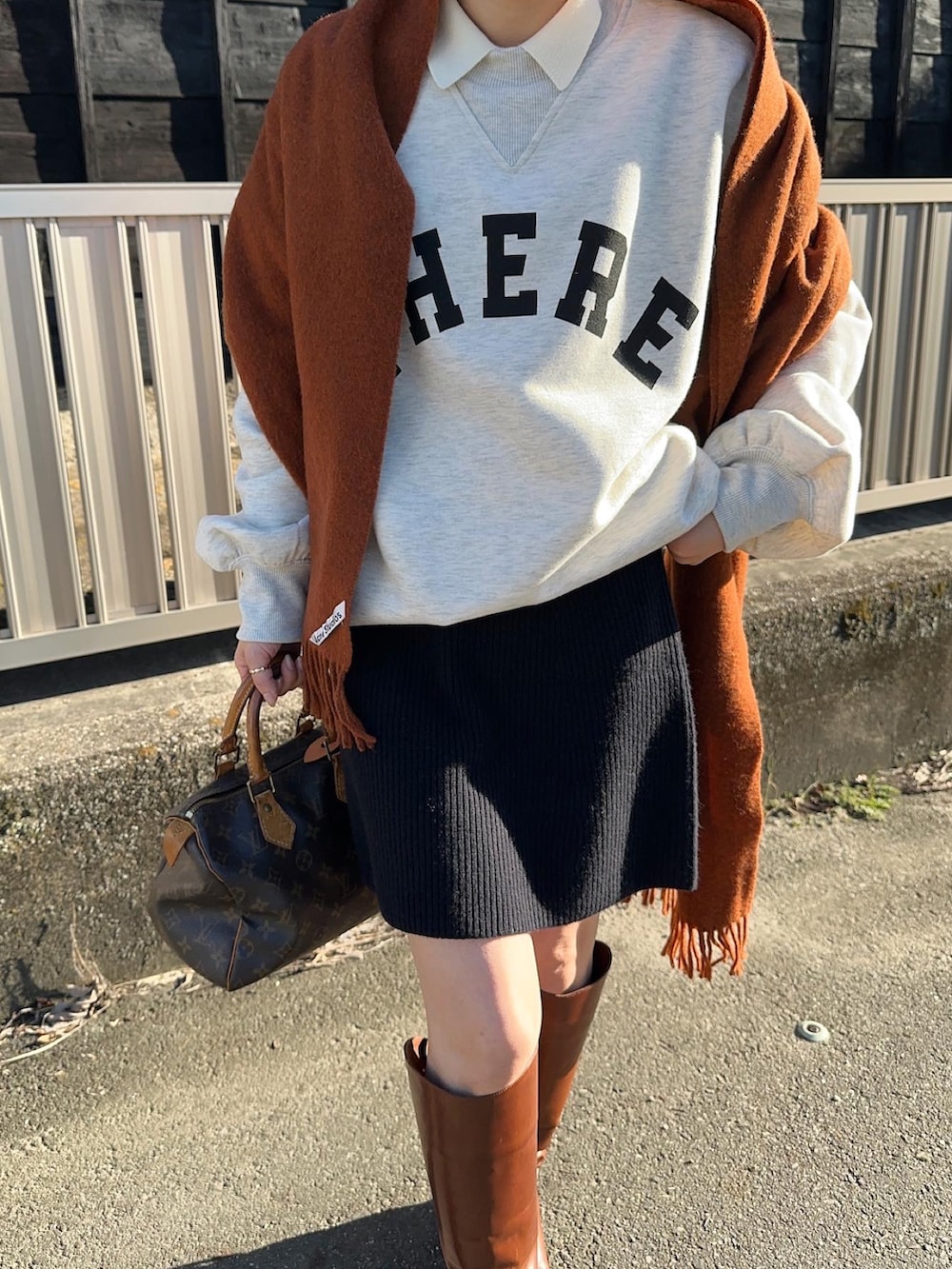 ベージュ系のスウェット、ブルー系のスカート、ブラウン系のブーツを着用したレディースの秋コーディネートの2枚目の写真
