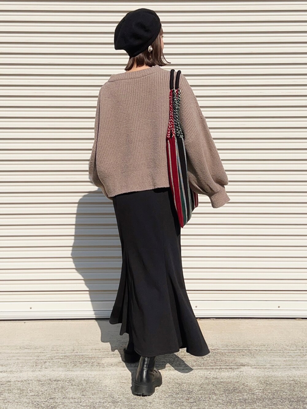 ブラック系のブーツ、レッド系のトートバッグ、グレー系のニット/セーターを着用したレディースの秋コーディネートの2枚目の写真