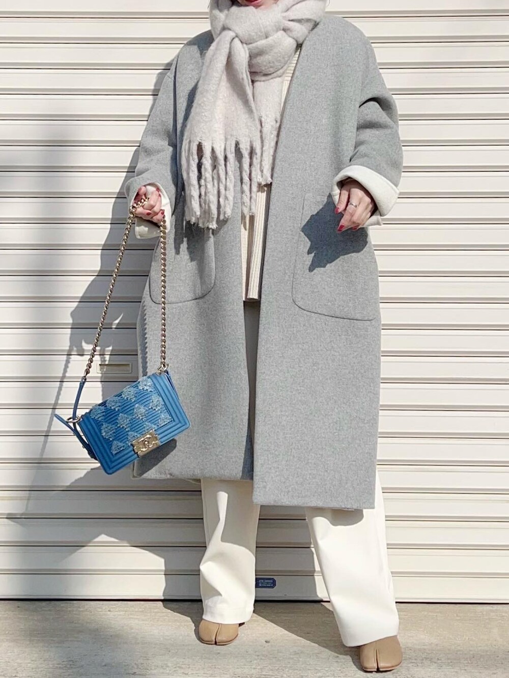 ホワイト系のニット/セーター、ホワイト系のスラックス、ベージュ系のブーツを着用したレディースの冬コーディネートの4枚目の写真